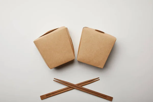 Vue de dessus des boîtes de wok disposées et des baguettes sur la surface blanche, concept minimaliste — Photo de stock