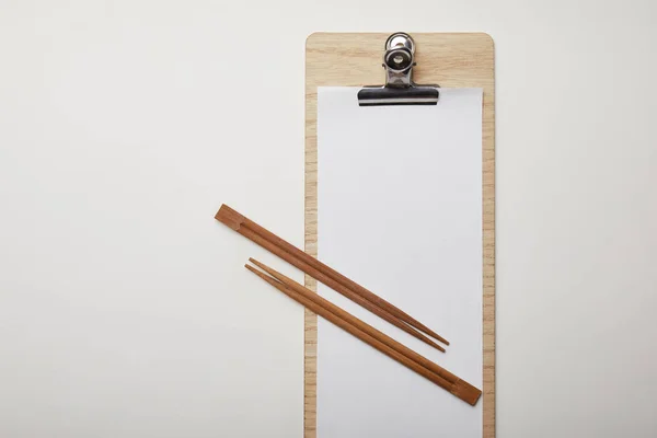 Top view of blank menu and chopsticks on white surface, minimalistic concept — Stock Photo