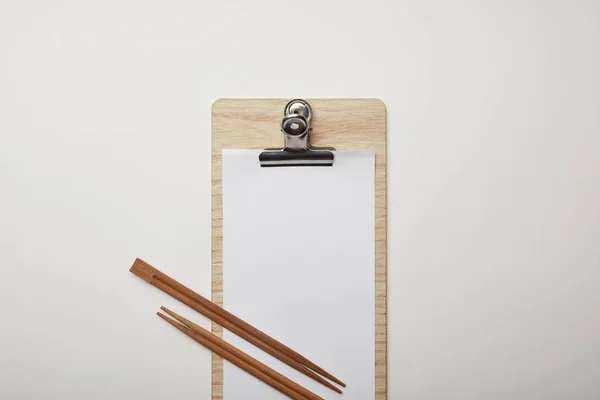 Pose plate avec menu blanc et baguettes sur surface blanche, concept minimaliste — Photo de stock