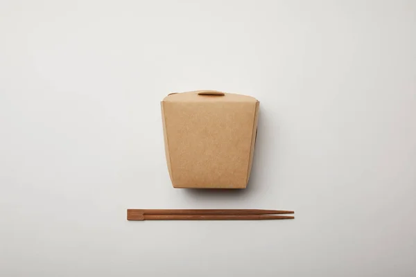 Vista elevada de palillos dispuestos y caja de fideos en la superficie blanca, concepto minimalista — Stock Photo