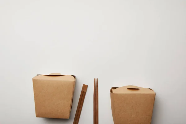 Vue de dessus des baguettes disposées et des boîtes à nouilles sur surface blanche, concept minimaliste — Photo de stock