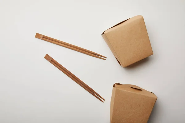 Vue de dessus des baguettes disposées et des boîtes à nouilles sur surface blanche, concept minimaliste — Photo de stock