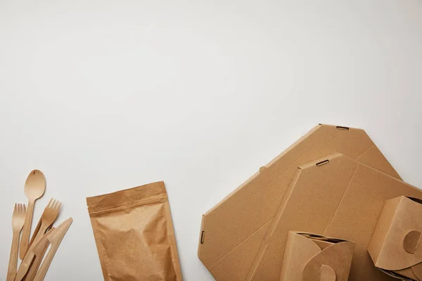 Vue surélevée des boîtes à pizza et nouilles avec couteaux et fourchettes jetables sur surface blanche — Photo de stock