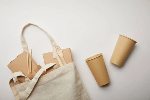 Flat lay com saco de algodão com caixas de alimentos e duas xícaras de café descartáveis na superfície branca — Fotografia de Stock