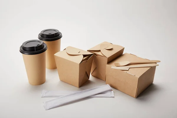 Einweggabel mit Messer, Essstäbchen, Kaffeetassen aus Papier und Lebensmittelkartons aus Karton auf weiß — Stockfoto