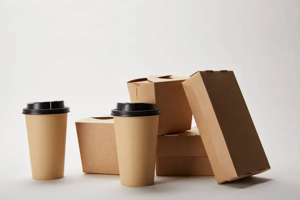 Tazas de café desechables y cajas de cartón sobre blanco — Stock Photo