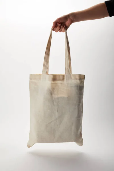 Imagen recortada de mujer sosteniendo bolsa de algodón con entrega de alimentos en blanco - foto de stock