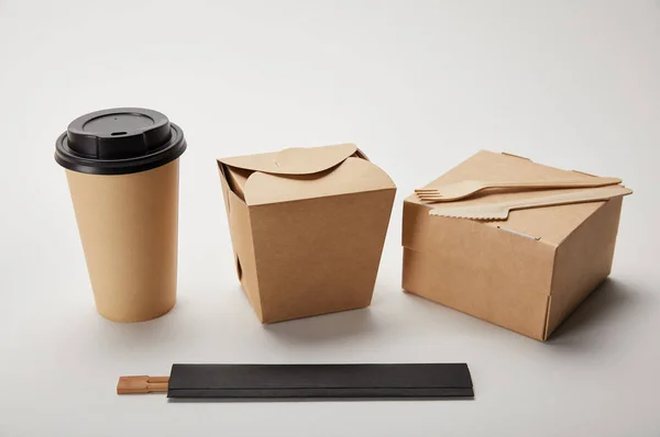 Primer plano vista de la taza de café de papel, cajas de alimentos y palillos en blanco - foto de stock