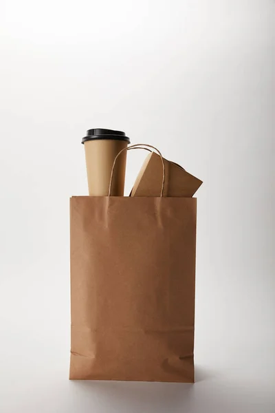 Vista da vicino del sacchetto di carta di consegna del cibo con tazza di caffè usa e getta e scatola wok su bianco — Foto stock