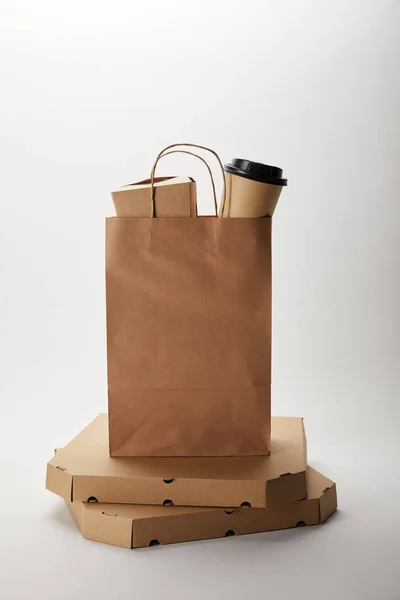 Pizzakartons und Papiertüte mit Einweg-Kaffeetasse und Wok-Box auf weiß — Stockfoto
