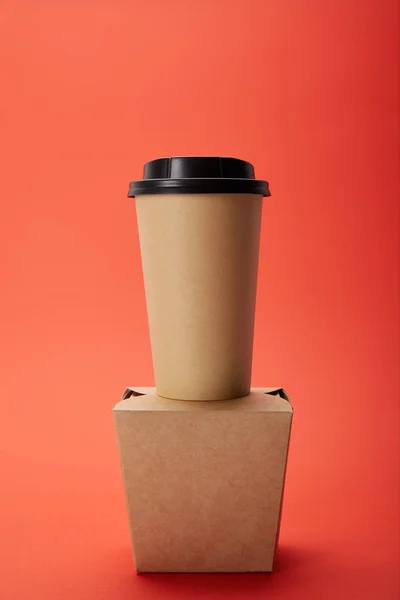 Vista de cerca de la taza de café desechable y la caja de fideos en rojo, concepto minimalista - foto de stock