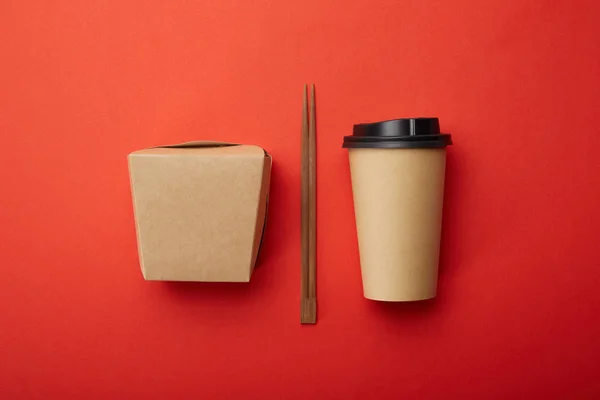 Flache Lage mit Essstäbchen, Nudelbox und Einwegbecher Kaffee auf roter Oberfläche, minimalistisches Konzept — Stockfoto