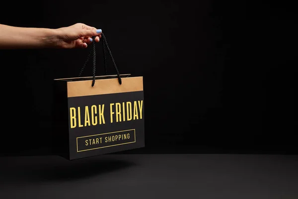 Partial view of woman holding black shopping bag with black friday sale - start shopping — Stock Photo