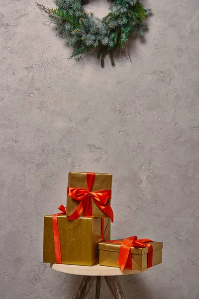 Goldene Weihnachtsgeschenkboxen auf Stuhl unter Tannenkranz im Zimmer — Stockfoto
