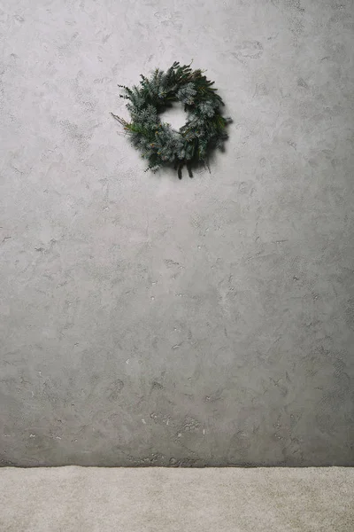 Green fir wreath for Christmas decoration hanging on grey wall in room — Stock Photo