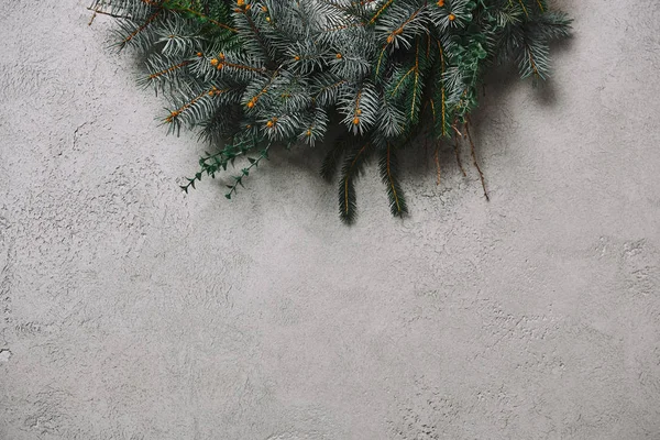 Cropped image of fir wreath for Christmas decoration hanging on grey wall in room — Stock Photo