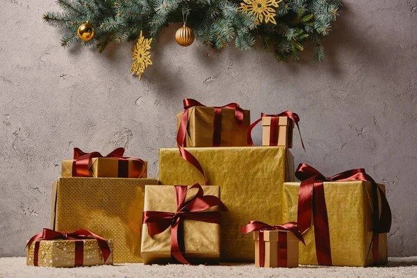 Pila de cajas de regalo de Navidad de oro en la alfombra en la habitación bajo el árbol de Navidad - foto de stock