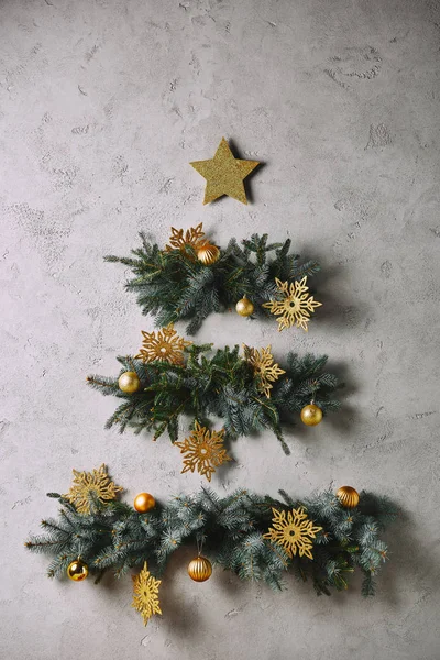 Árbol de Navidad hecho a mano y estrella colgando en la pared gris en la habitación - foto de stock