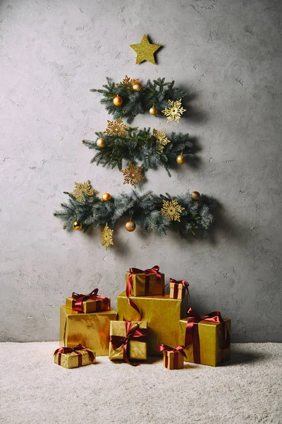 Handgefertigter Weihnachtsbaum und Stern hängen an grauer Wand, Geschenkboxen am Boden im Zimmer — Stockfoto