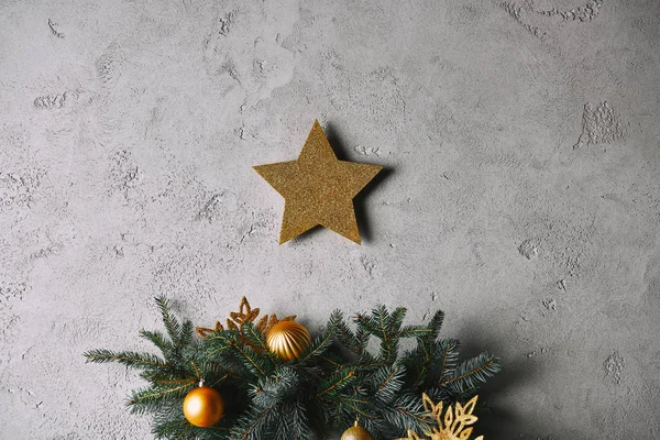 Estrella de oro de Navidad colgando en la pared gris por encima del árbol de Navidad en la habitación - foto de stock