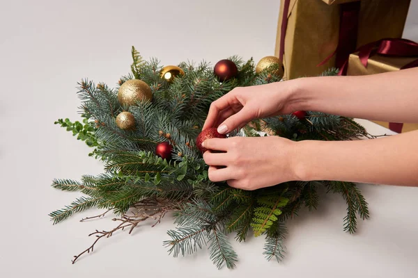 Imagen recortada de la mujer decorando la corona de abeto de Navidad con juguetes aislados en blanco - foto de stock