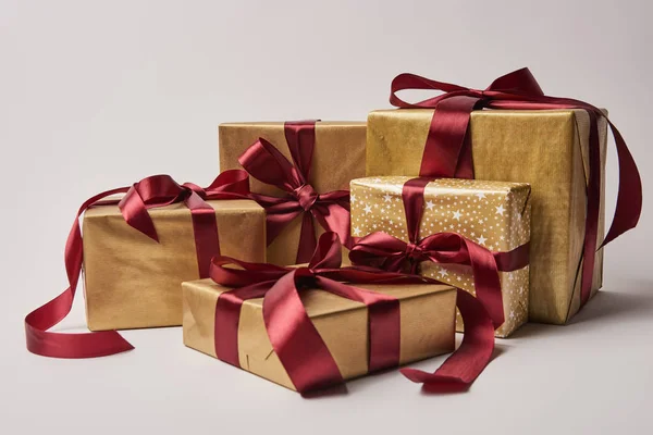 Золоті різдвяні подарункові коробки з бордовими стрічками ізольовані на білому — стокове фото