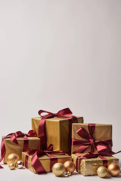 Gift boxes with burgundy ribbons and golden christmas balls isolated on white — Stock Photo