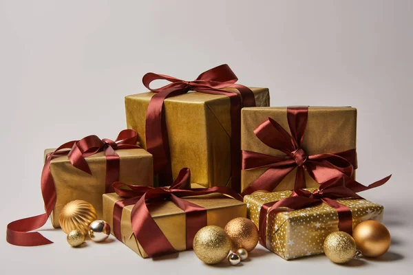 Golden Christmas gift boxes with burgundy ribbons and baubles isolated on white — Stock Photo