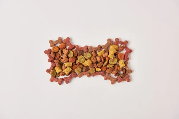 Flay lay with bone made of dog food on white surface — Stock Photo