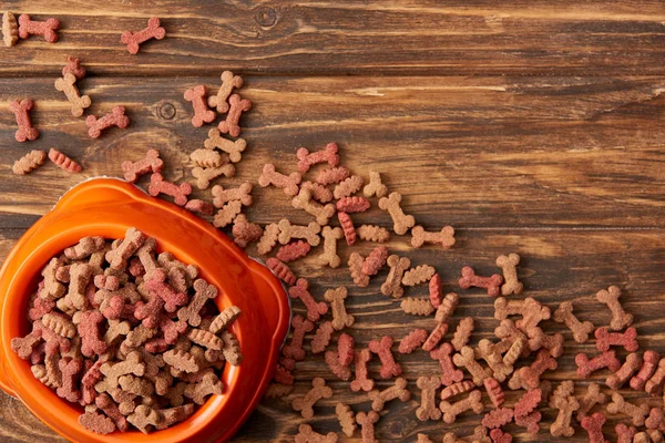 Vue du dessus du bol en plastique avec pile de nourriture pour chien sur fond en bois — Photo de stock