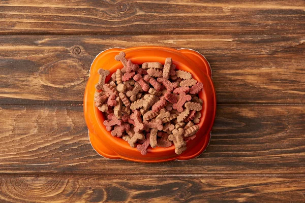 Vue du dessus du bol en plastique avec pile de nourriture pour chien sur fond en bois — Photo de stock