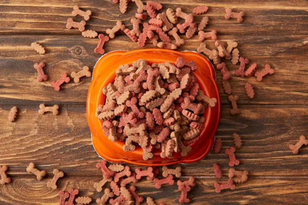 Erhöhter Blick auf Plastikschüssel mit Haufen Hundefutter auf Holztisch — Stockfoto