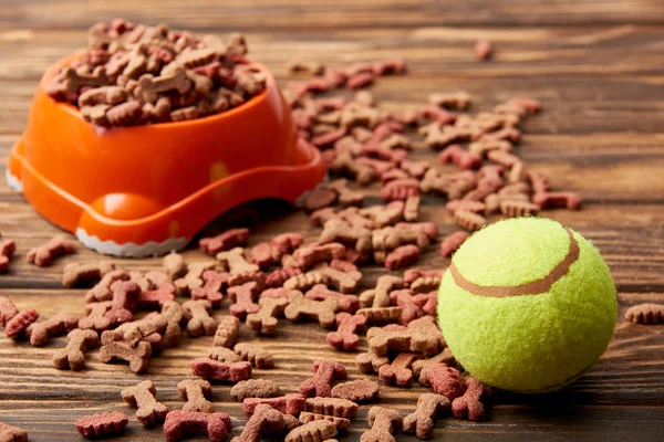 Selective focus of plastic bowl with dog food and ball on wooden table — Stock Photo