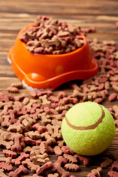 Close up view of plastic bowl with dog food and ball on wooden table — Stock Photo