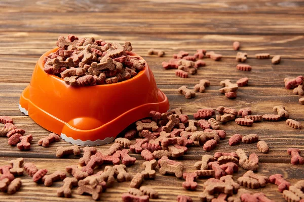 Plastikschale mit Haufen Hundefutter auf Holztisch — Stockfoto