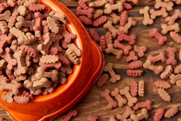 Selective focus of plastic bowl with pile of dog food on wooden table — Stock Photo