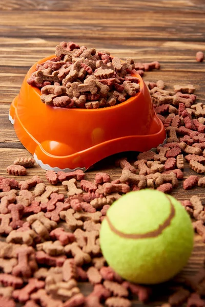 Close up view of plastic bowl with dog food and ball on wooden table — Stock Photo