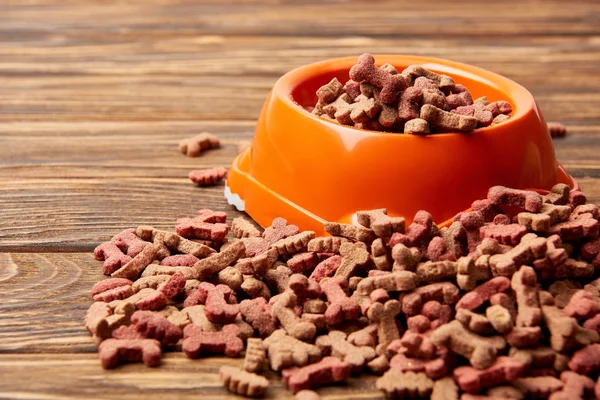 Close up view of plastic bowl with pile of dog food on wooden table — Stock Photo