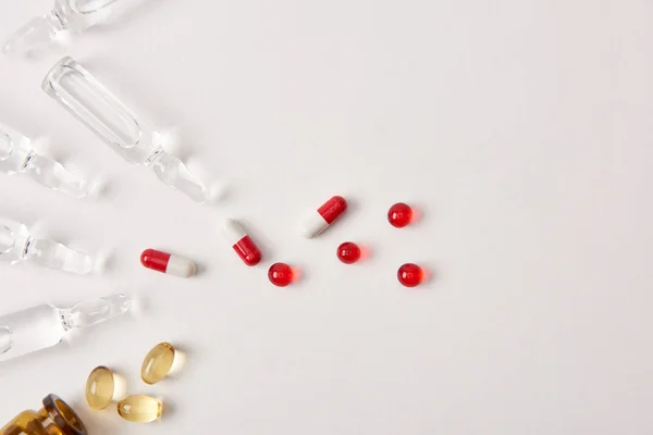 Вид сверху различных таблеток и ампул с лекарствами на белой поверхности — стоковое фото