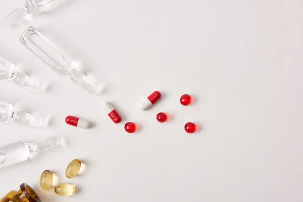 Top view of various pills and ampoules with medicament on white surface — Stock Photo