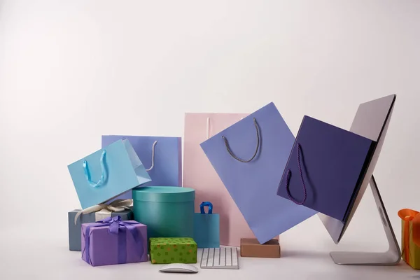 Side view of various boxes with shopping bags going out of computer screen, black friday concept — Stock Photo