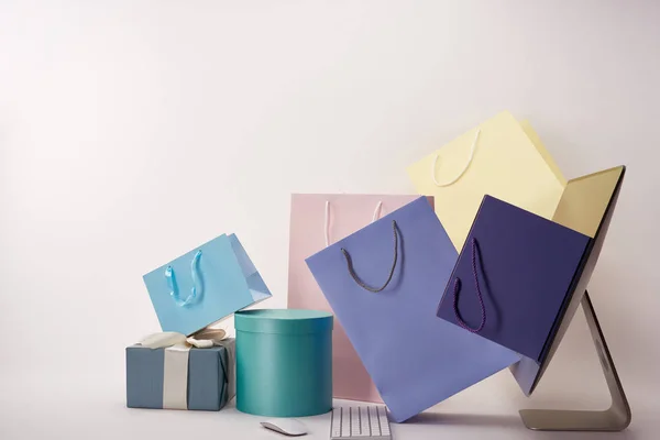 Side view of computer and various colorful boxes with bags on white, black friday concept — Stock Photo