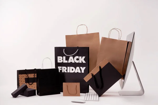 Seitenansicht von Computer und Schachteln mit Einkaufstaschen mit schwarzem Freitagsschild auf weißem Hintergrund — Stockfoto