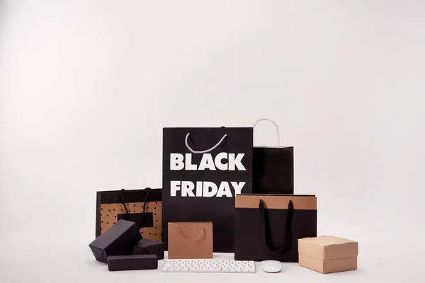 Teclado do computador com mouse e várias caixas com sacos de compras com sinal de sexta-feira preto no branco — Fotografia de Stock
