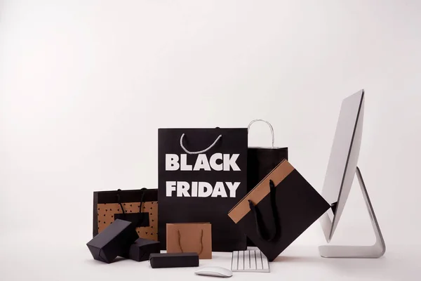 Seitenansicht des Computers und verschiedener Kartons mit Einkaufstaschen mit schwarzem Freitagsschild auf weißem Hintergrund — Stockfoto