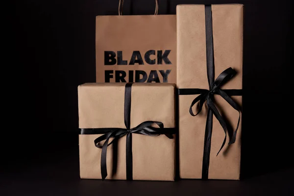 Cajas de regalo envueltas y bolso de compras de viernes negro en superficie negra - foto de stock