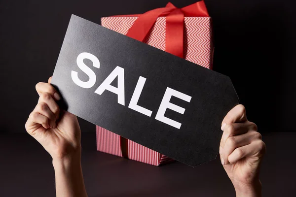 Cropped shot of woman holding banner with sale inscription in front of stacked gift boxes, black friday concept — Stock Photo