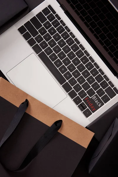 Top view of laptop with black friday button on keyboard and shopping bag on black — Stock Photo