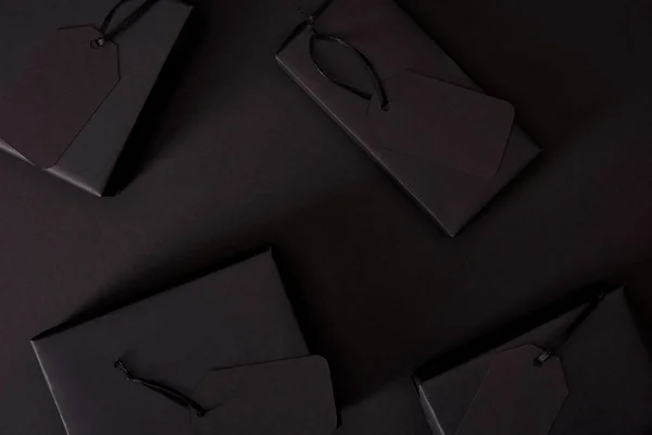 Vista superior de cajas negras con etiquetas en la superficie negra, concepto de viernes negro - foto de stock