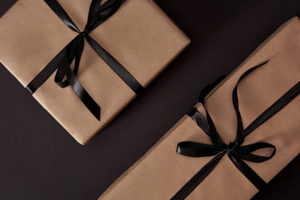 Vista superior de las cajas de regalo envueltas artesanalmente en la superficie negra, concepto de viernes negro — Stock Photo